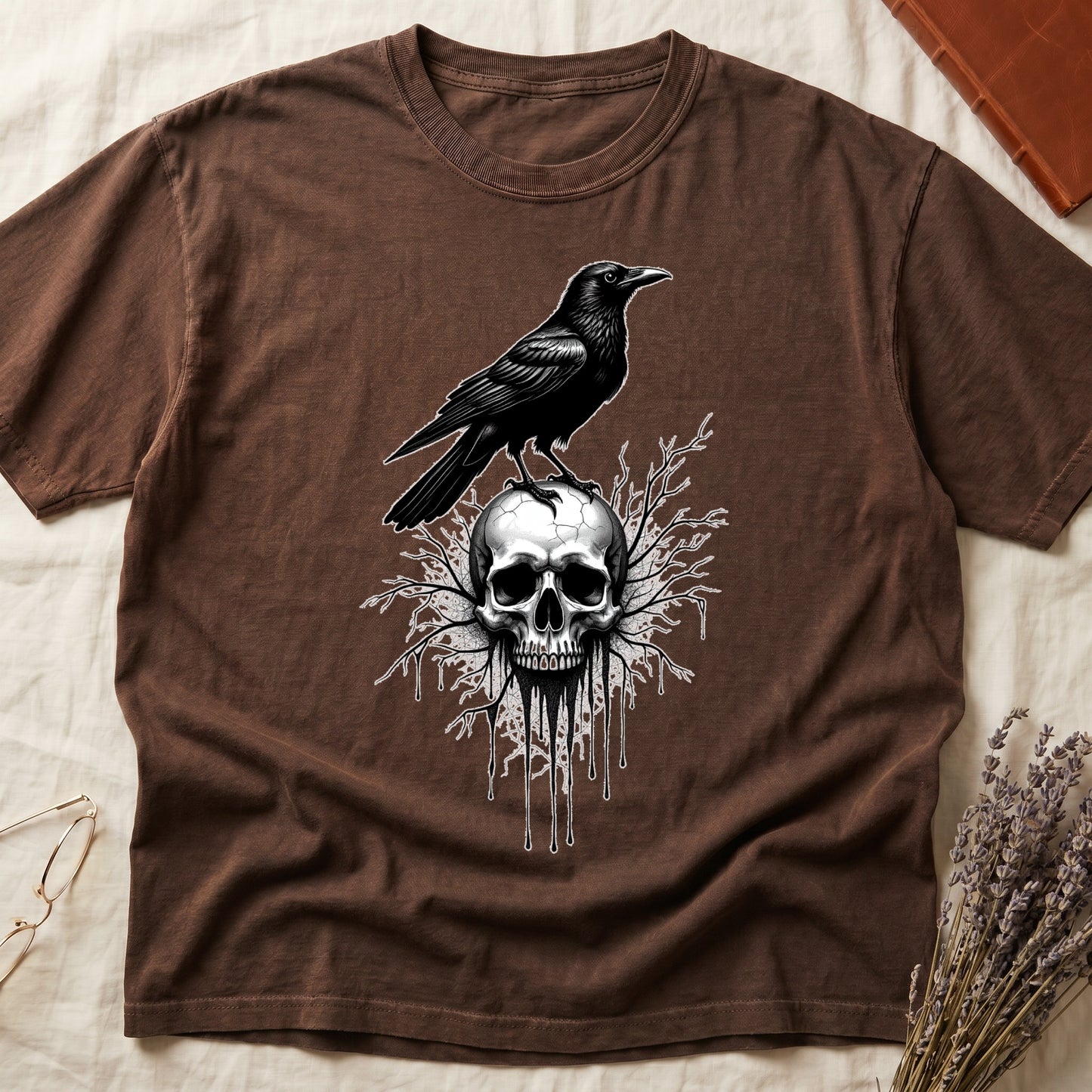 Espresso tee with raven silhouette on human skull, ink drips from jaw, bare branches behind, monochrome illustration.