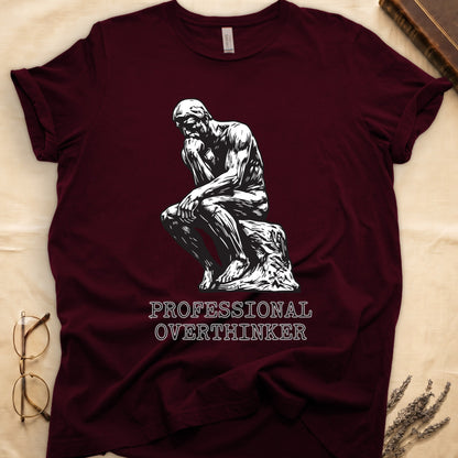 Maroon tee with monochrome rendering of Rodin's Thinker, "PROFESSIONAL OVERTHINKER" in serif capitals below.