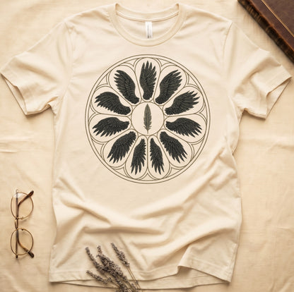 Natural tee with sepia rose-window of eight feathered wings around central feather, engraved linework on parchment ground.