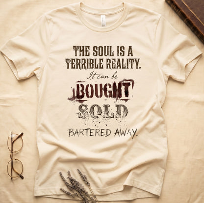Natural tee with distressed western type, "THE SOUL IS A TERRIBLE REALITY. It can be BOUGHT SOLD BARTERED AWAY."