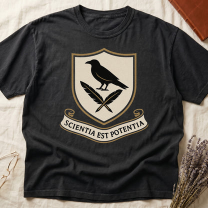 Black tee with cream-and-gold heraldic shield, black raven over crossed quills, scroll banner "SCIENTIA EST POTENTIA" below.