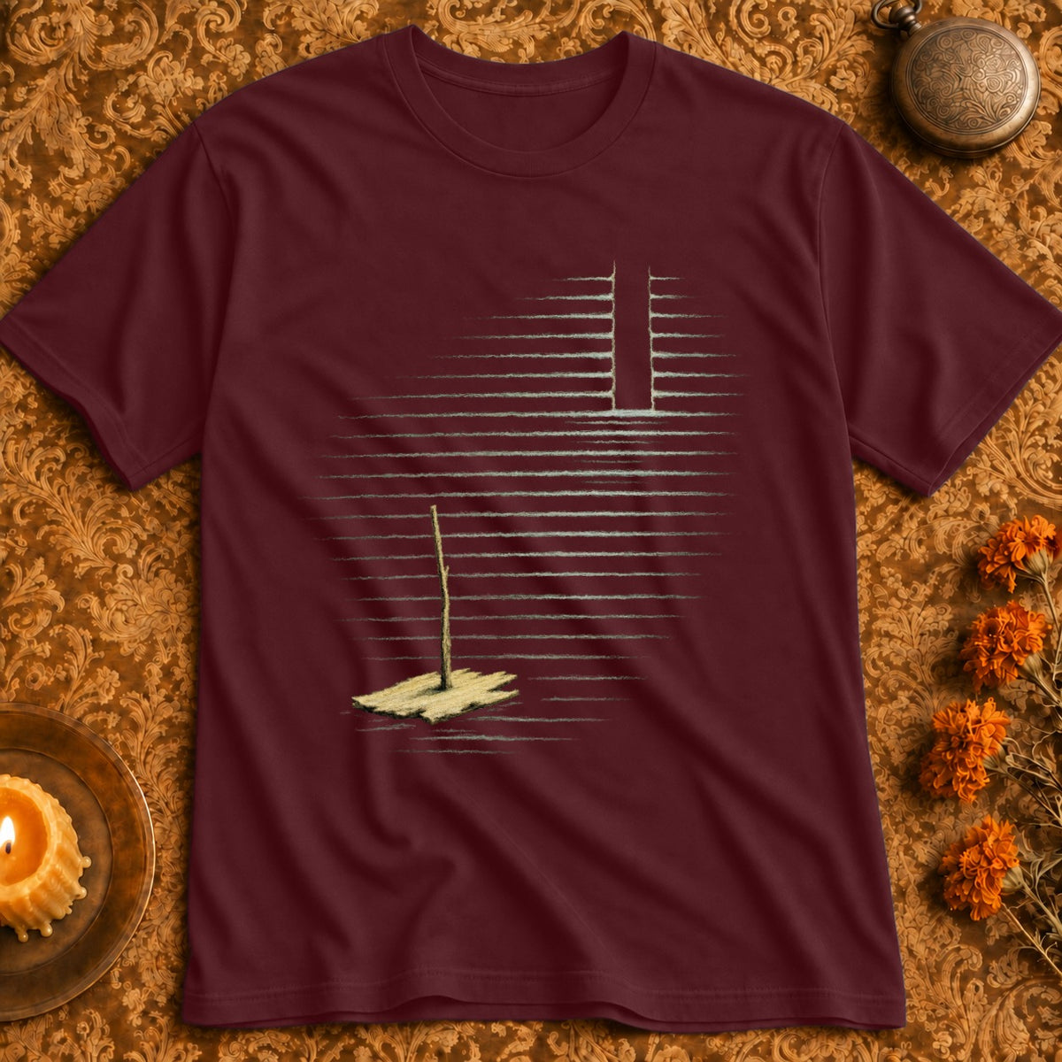 Maroon t-shirt with an abstract graphic of a single stick in sand under horizontal lines.