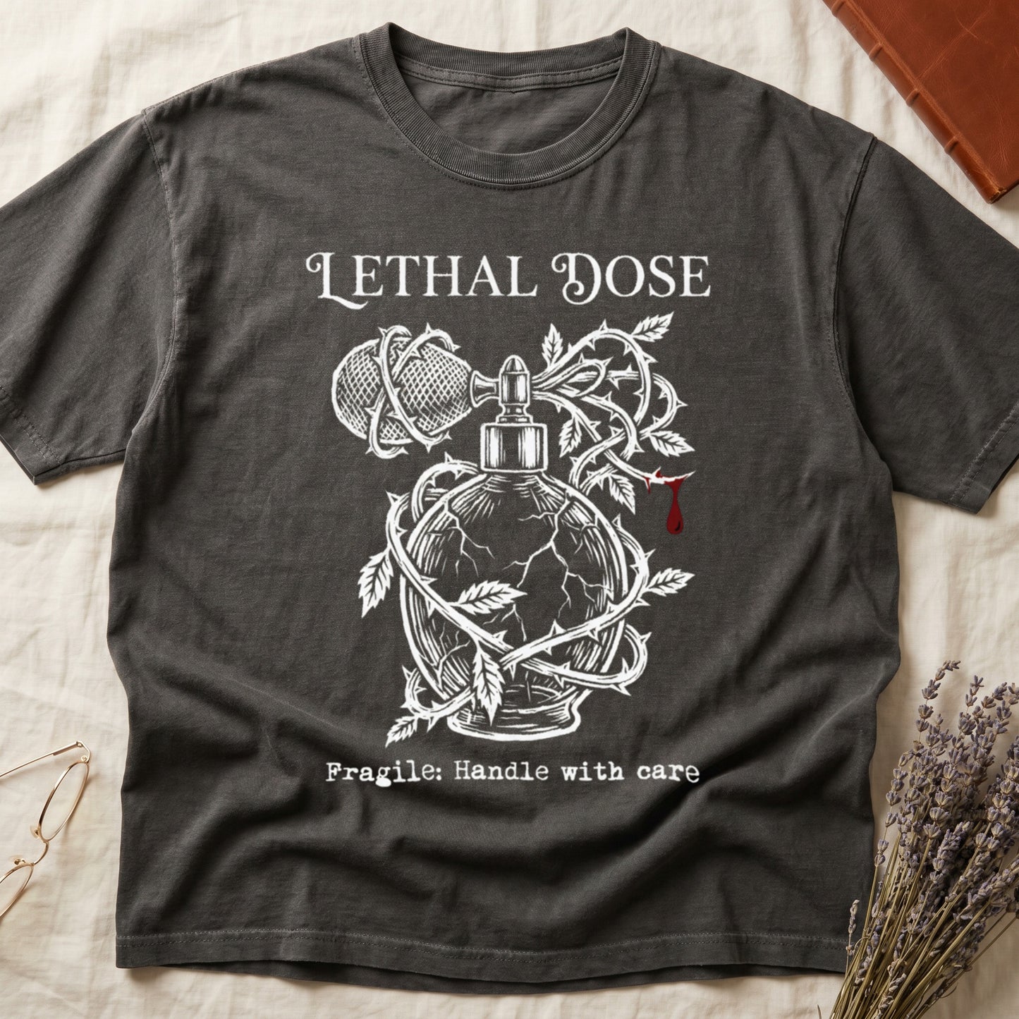 Pepper tee with cracked perfume bottle wrapped in thorns, blood drop, "LETHAL DOSE" top, "Fragile: Handle with care" below.