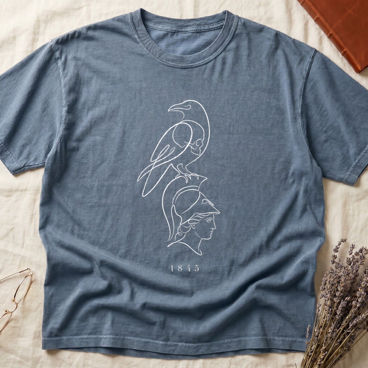 Blue t-shirt with white outline design of a raven over a classical profile and the year 1815.