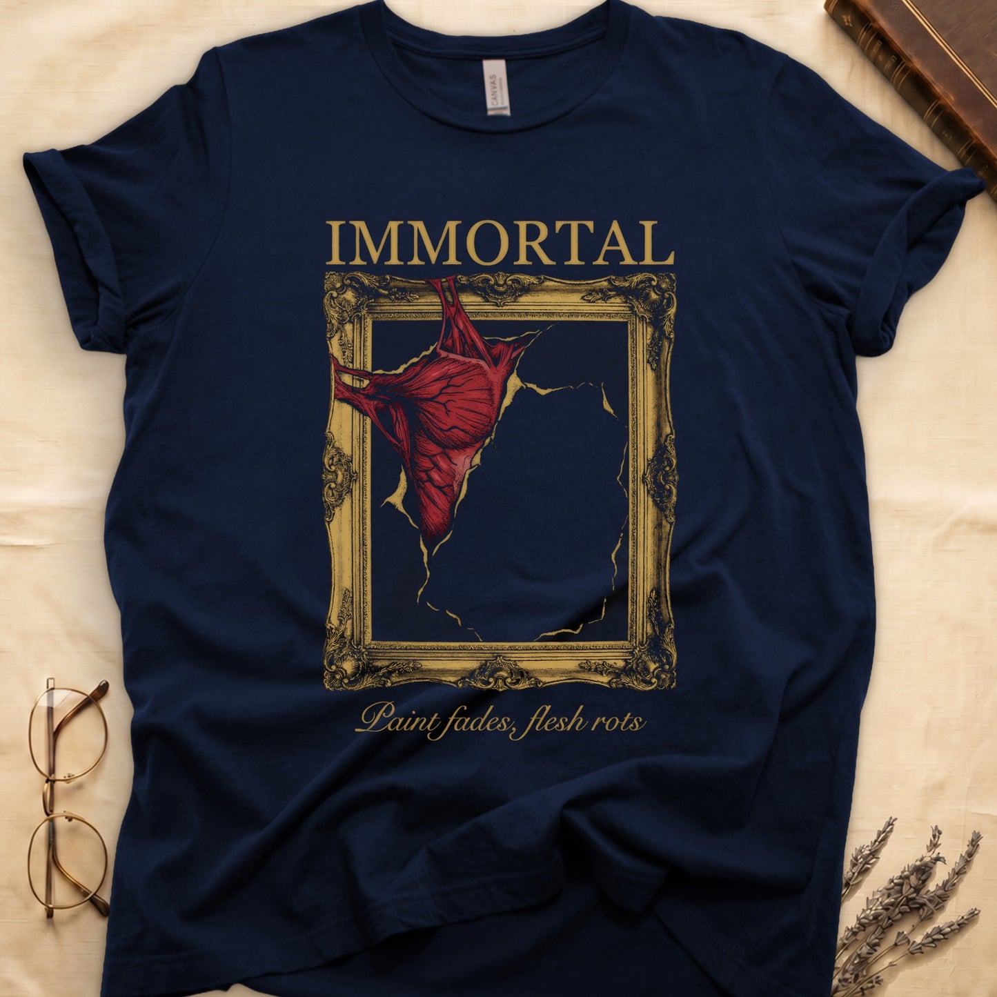 Navy tee with gold frame and exposed muscle tearing canvas, "IMMORTAL" top, "Paint fades, flesh rots" italic below.