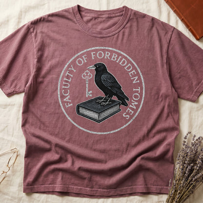 Blue Jean tee with circular badge, raven on closed book holding key, "FACULTY OF FORBIDDEN TOMES" curved around in cream.
