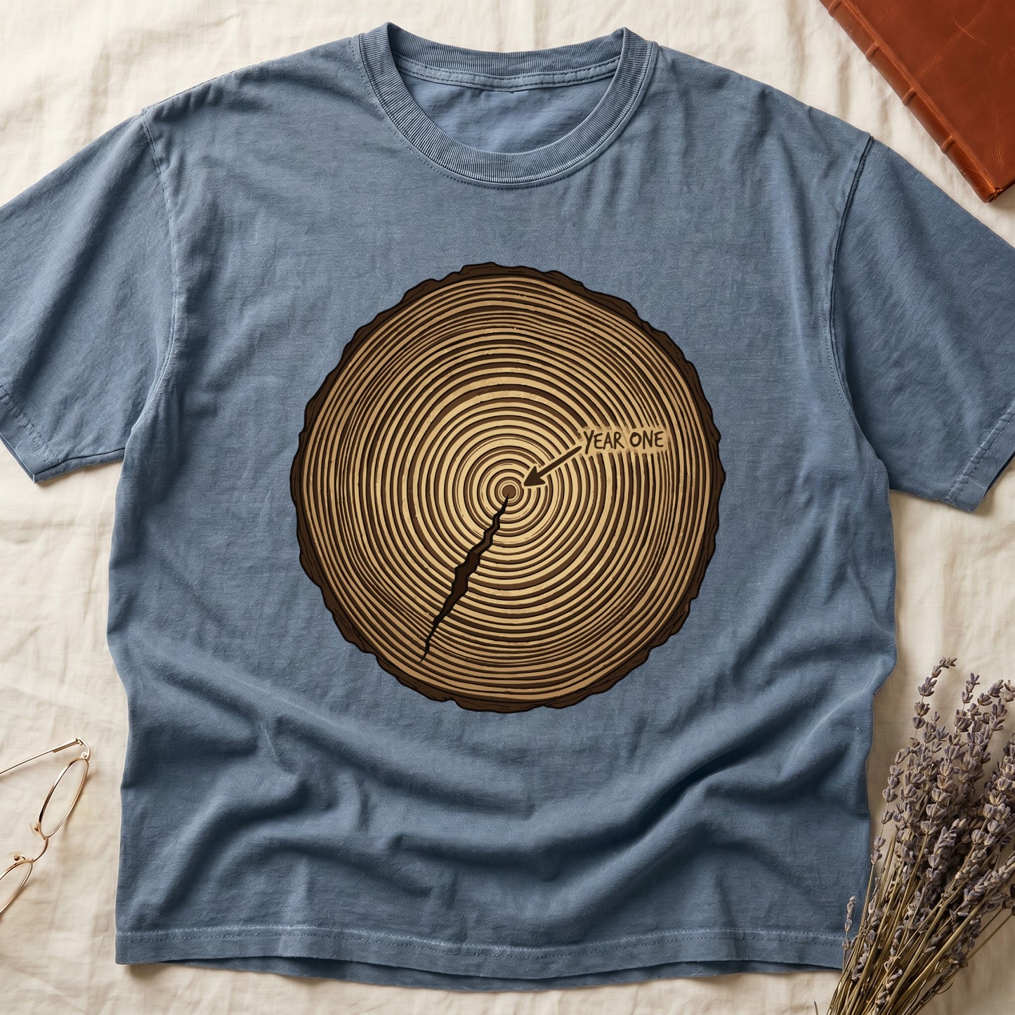 Blue Jean tee with cross-section of tree rings in warm brown, arrow pointing to center labeled "YEAR ONE" in serif type.
