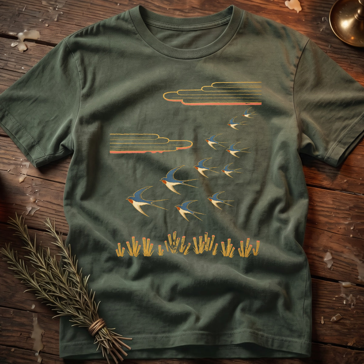 Green t-shirt with a flock of swallows flying above stylized reeds and clouds.