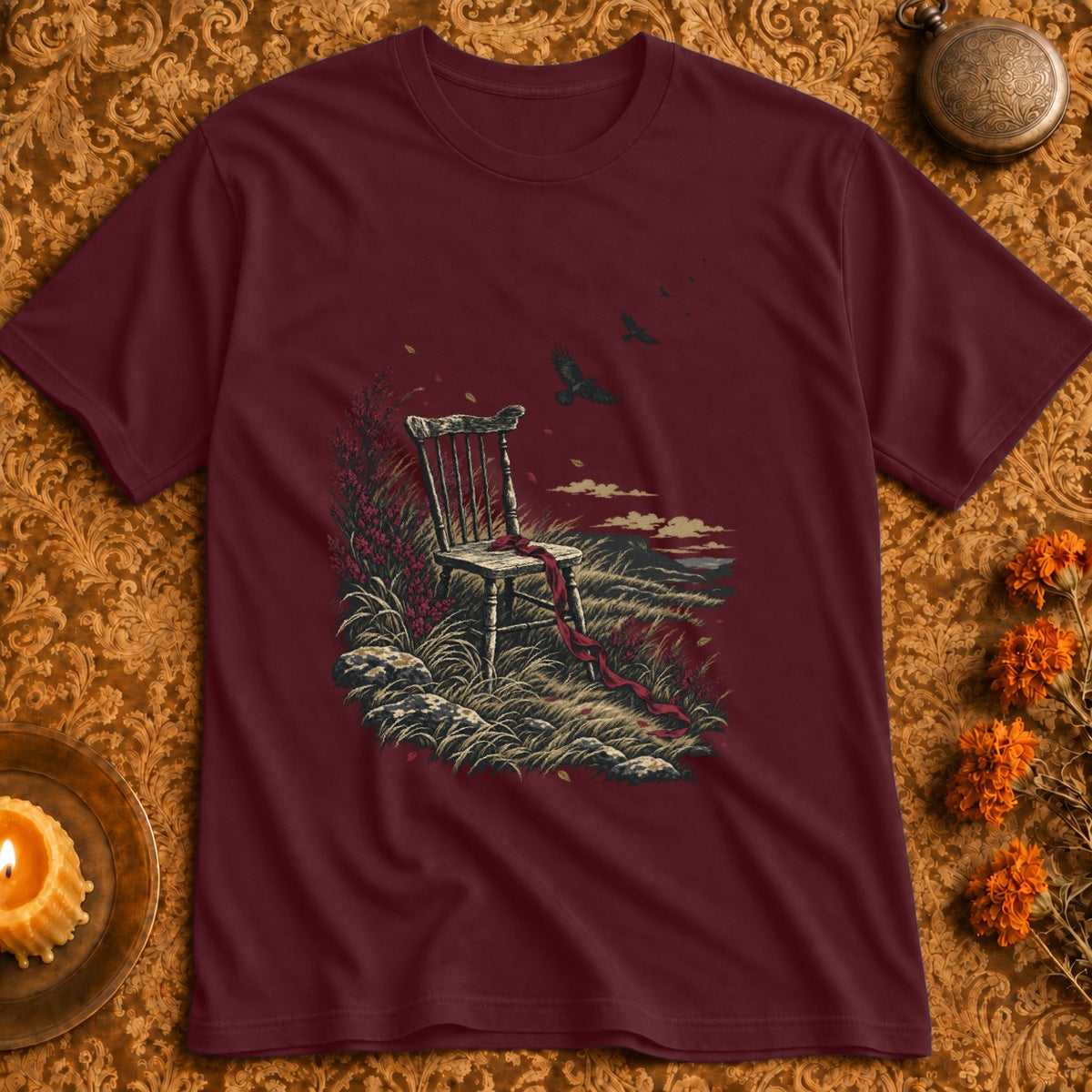 Maroon t-shirt with a graphic of an empty chair in a grassy landscape with birds.
