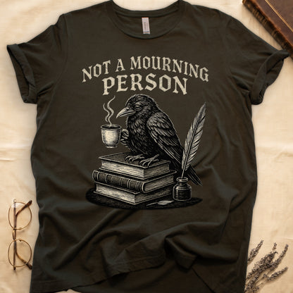 Maroon tee with raven holding coffee on stack of books, quill in inkwell, "NOT A MOURNING PERSON" distressed serif top.