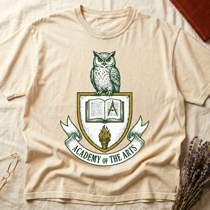 Ivory tee with heraldic shield crest, owl perched on top, open book and dividers center, "ACADEMY OF THE ARTS" on a banner.