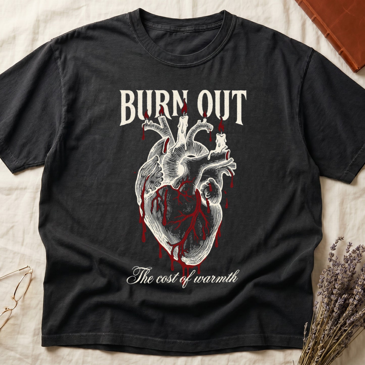 Black tee with anatomical heart and melted candles dripping red wax, "BURN OUT" top, "The cost of warmth" cursive below.