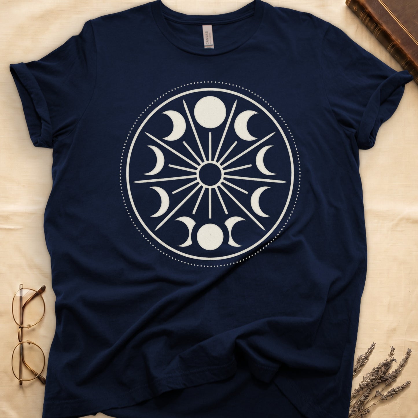 Navy tee with cream lunar orrery wheel, dotted ring, radial sunburst, moon phases around perimeter, central star.