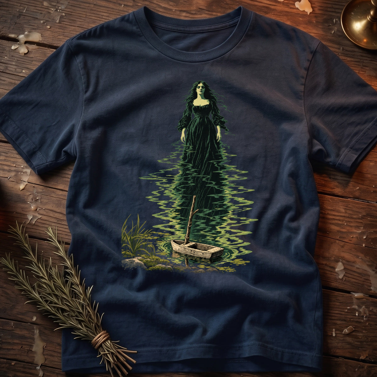 Dark blue t-shirt features a gothic woman in a green dress standing in water next to a small boat.