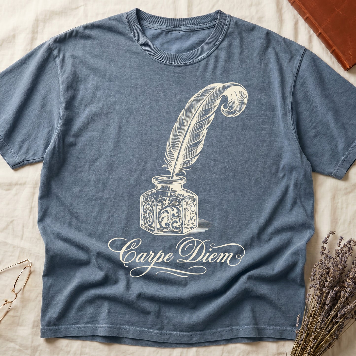 Blue Jean tee with ornate antique inkwell and quill pen in sepia linework, "Carpe Diem" in flowing cursive below.