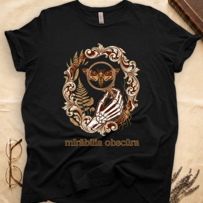 Black tee with skeletal hand, magnifying glass, death's-head moth, ferns on green, "mīrābilia obscūra" in Latin italic.