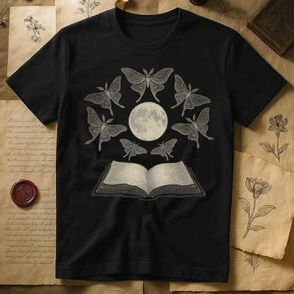 Black tee with full moon center, seven luna moths in halo around, open book below, cream-on-black engraving.