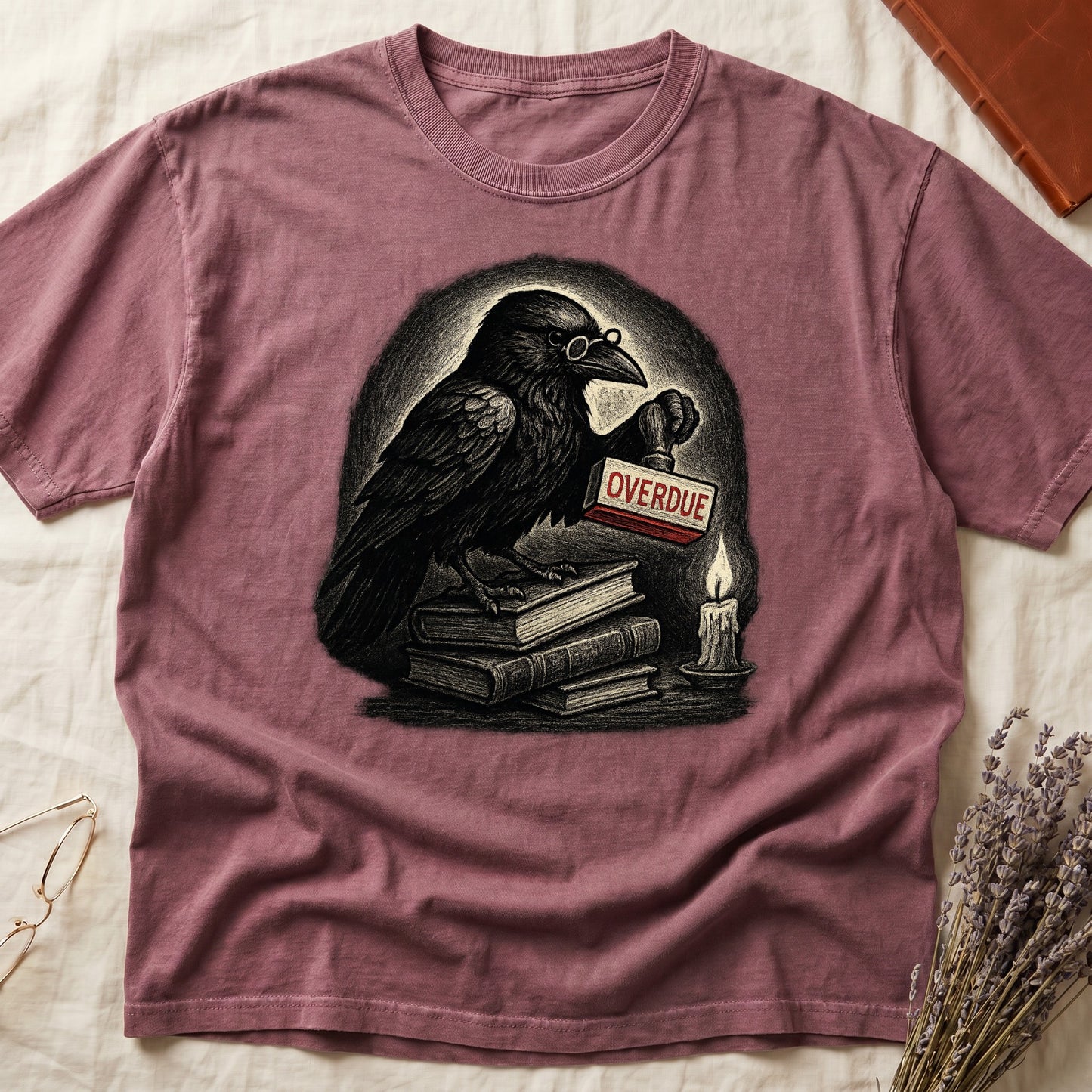 Dark Rose tee with bespectacled raven on stacked books, holding wooden "OVERDUE" stamp, lit candle beside, dawn glow behind.