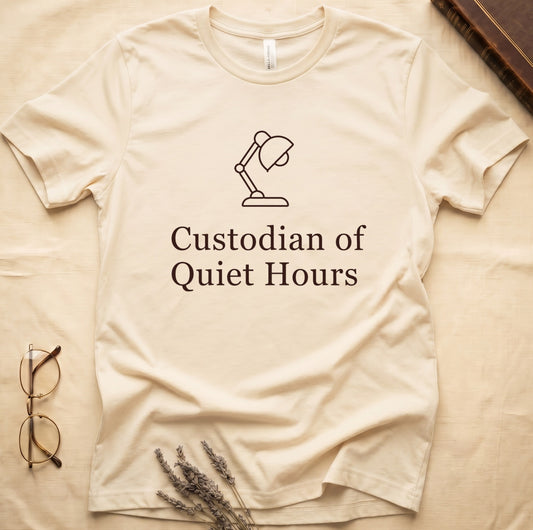 Natural tee with vintage desk lamp in cream linework above "Custodian of Quiet Hours" in distressed Art Deco caps.