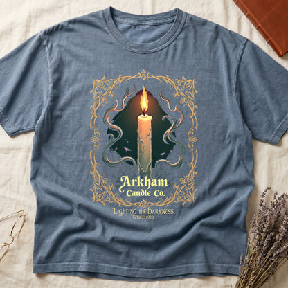 Blue Jean tee with lit candle, smoke, ornate gold filigree border, "Arkham Candle Co.," "Lighting the Darkness Since 1920."