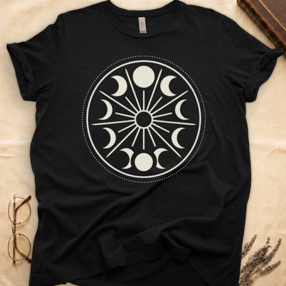 Black tee with cream lunar orrery wheel, dotted ring, radial sunburst, moon phases around perimeter, central star.
