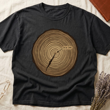 Black tee with cross-section of tree rings in warm brown, arrow pointing to center labeled "YEAR ONE" in serif type.