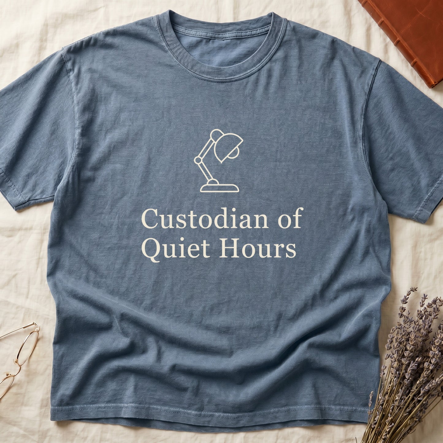Blue Jean tee with vintage desk lamp in cream linework above "Custodian of Quiet Hours" in distressed Art Deco caps.