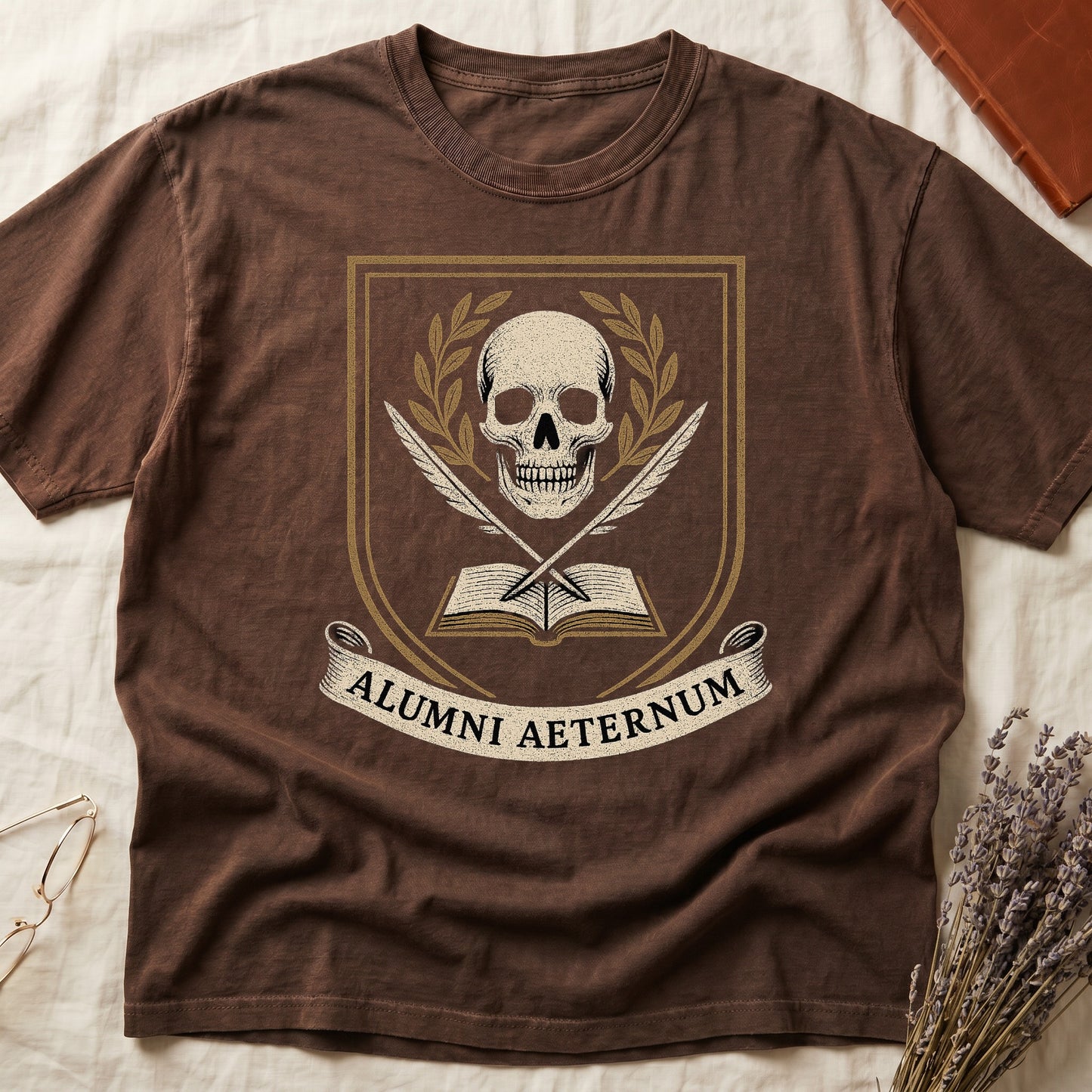Espresso tee with heraldic shield, skull and gold laurels, crossed quills, open book, scroll "ALUMNI AETERNUM" below.