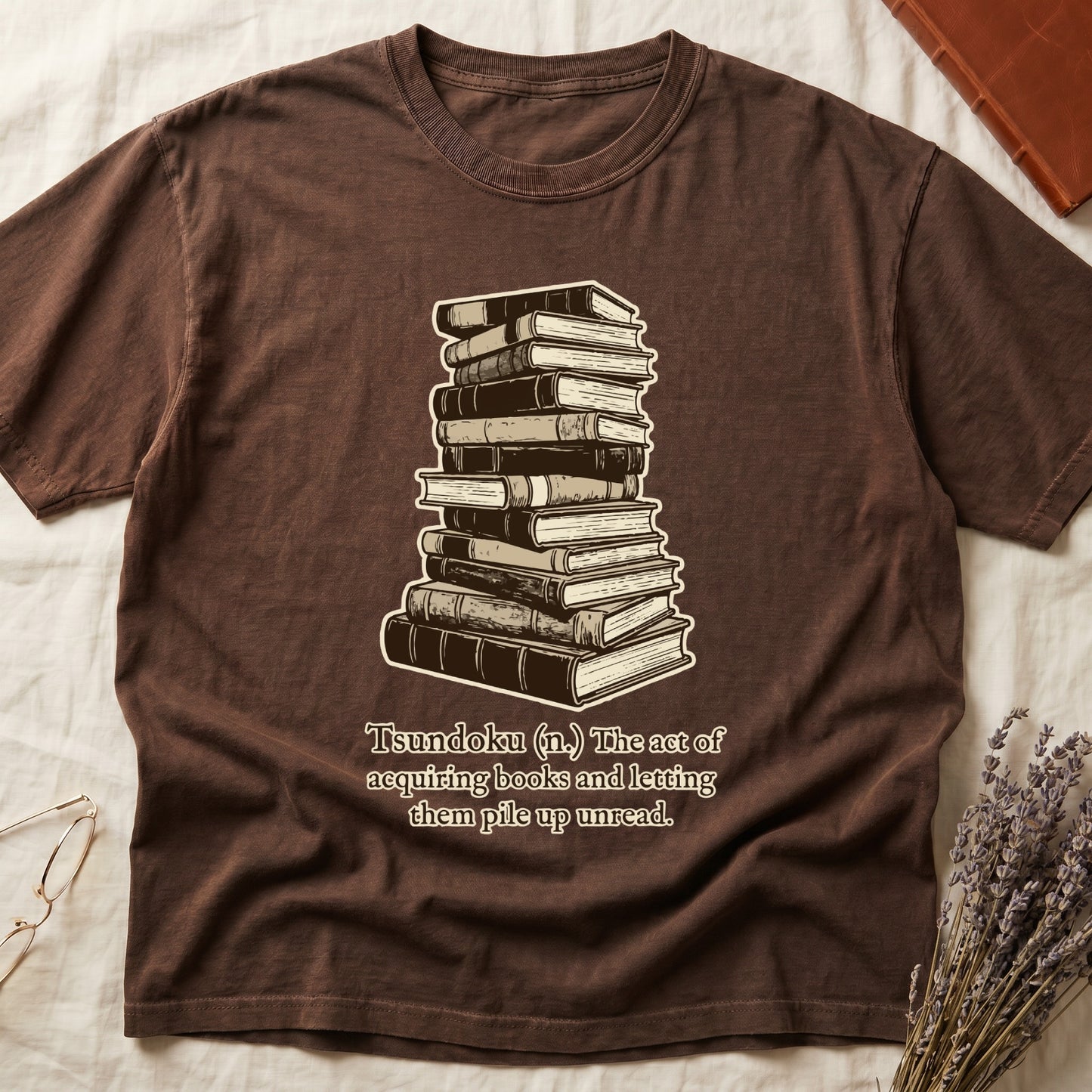 Espresso tee with stack of vintage hardcovers, "Tsundoku (n.) The act of acquiring books and letting them pile up unread."