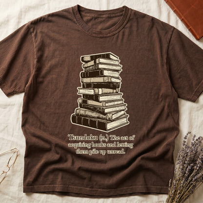 Espresso tee with stack of vintage hardcovers, "Tsundoku (n.) The act of acquiring books and letting them pile up unread."