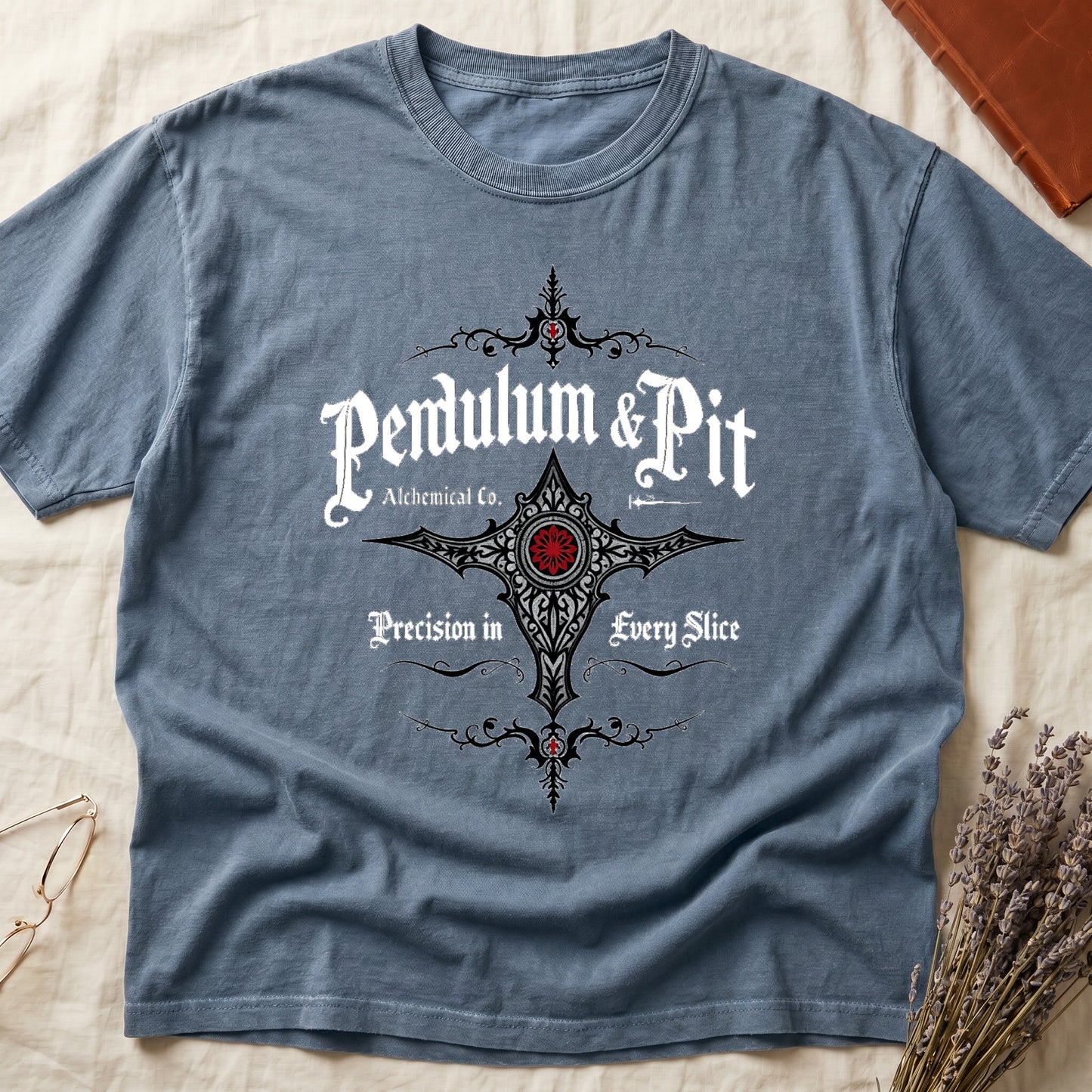 Blue Jean tee with white talismanic cross, "Pendulum & Pit Alchemical Co.," "Precision in Every Slice" banner ribbons.