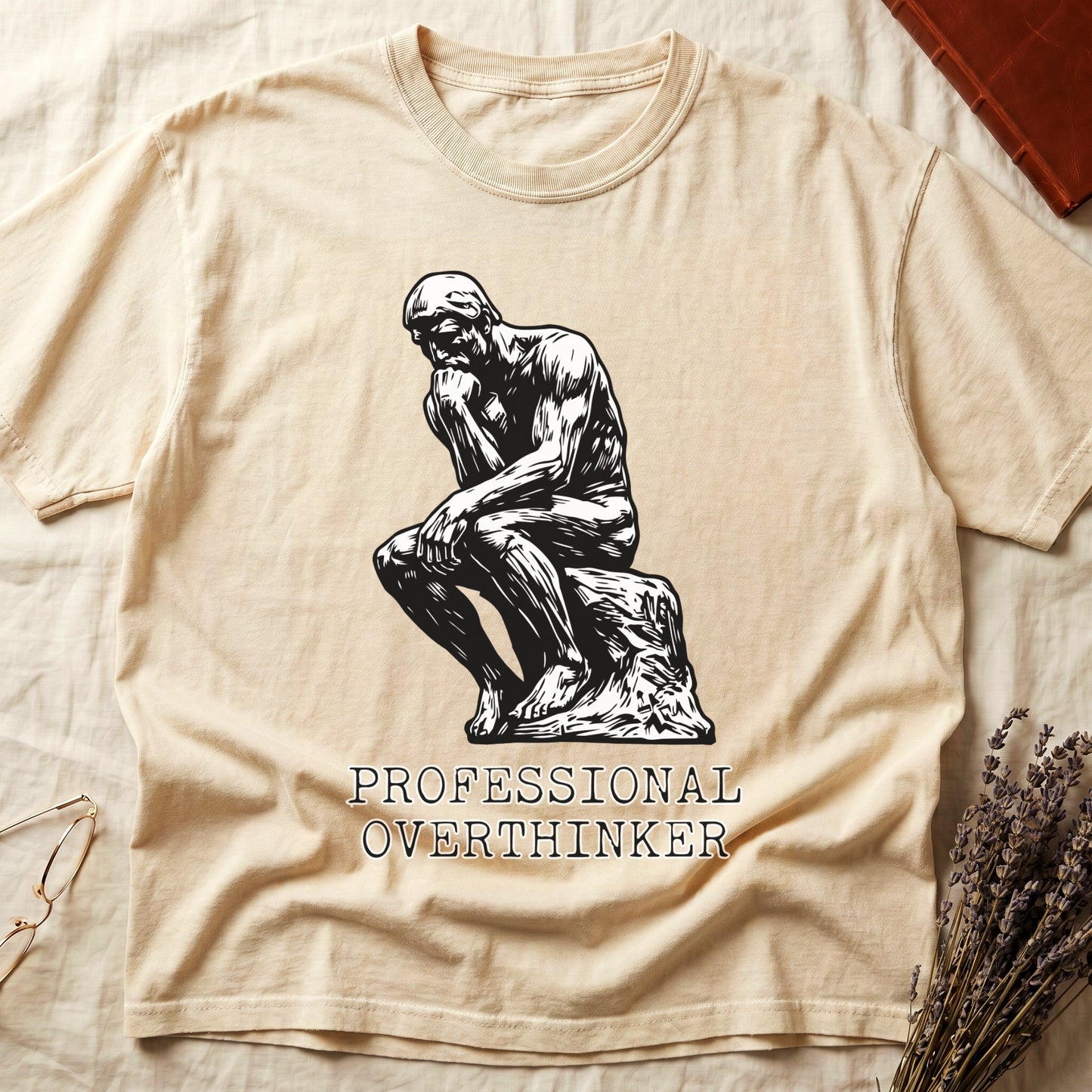 Ivory tee with monochrome rendering of Rodin's Thinker, "PROFESSIONAL OVERTHINKER" in serif capitals below.