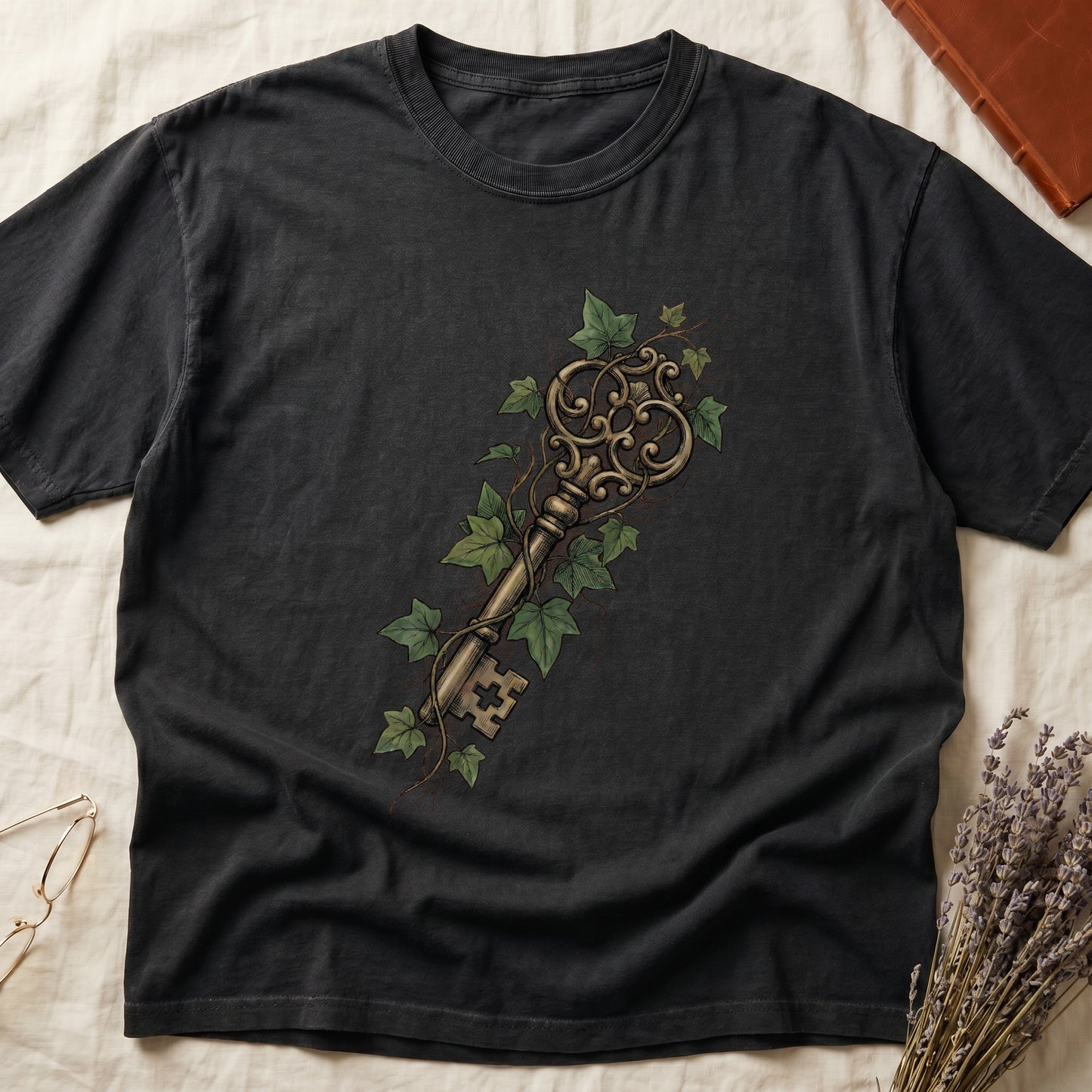 Black tee with ornate antique skeleton key in bronze, climbing English ivy in green on terracotta ground.