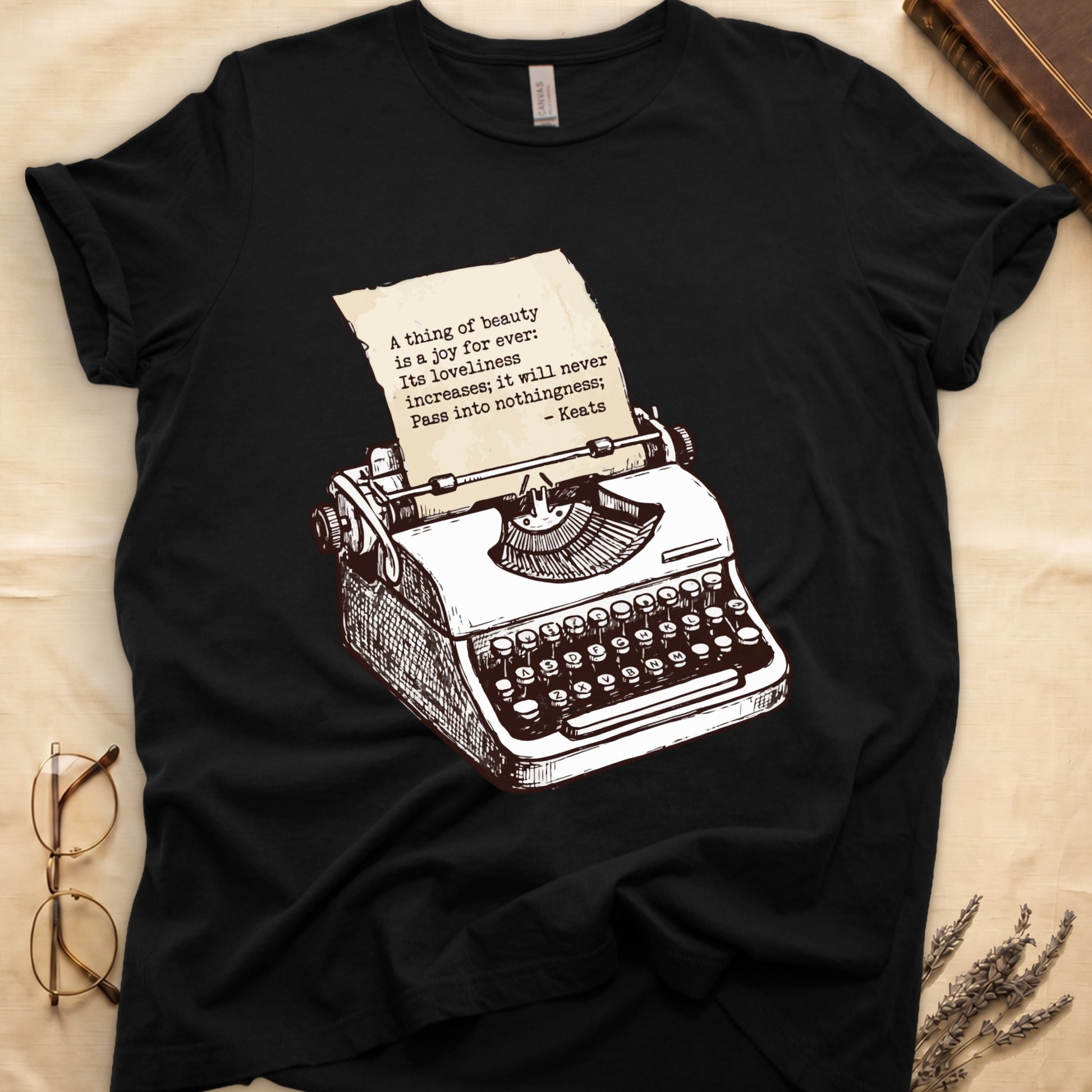Black tee with vintage typewriter in cream linework, paper showing "A thing of beauty is a joy for ever" by Keats.