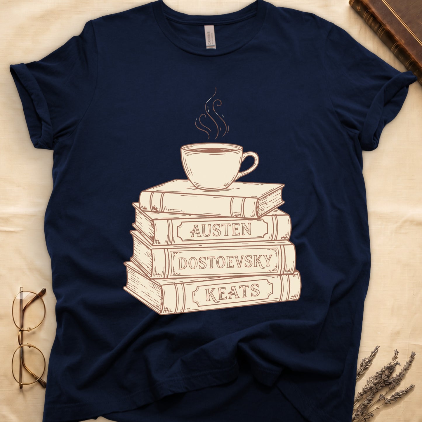 Navy tee with stack of vintage books labeled "AUSTEN," "DOSTOEVSKY," "KEATS" topped with a steaming coffee cup.