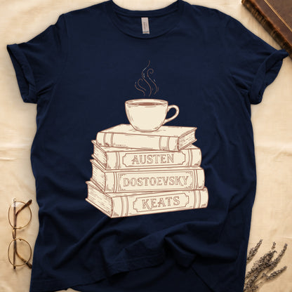 Navy tee with stack of vintage books labeled "AUSTEN," "DOSTOEVSKY," "KEATS" topped with a steaming coffee cup.