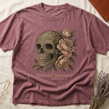Dark Rose tee with filigree-engraved skull on left, peach-cream peonies on right, crossed bones below, "Botanical Boneyard."