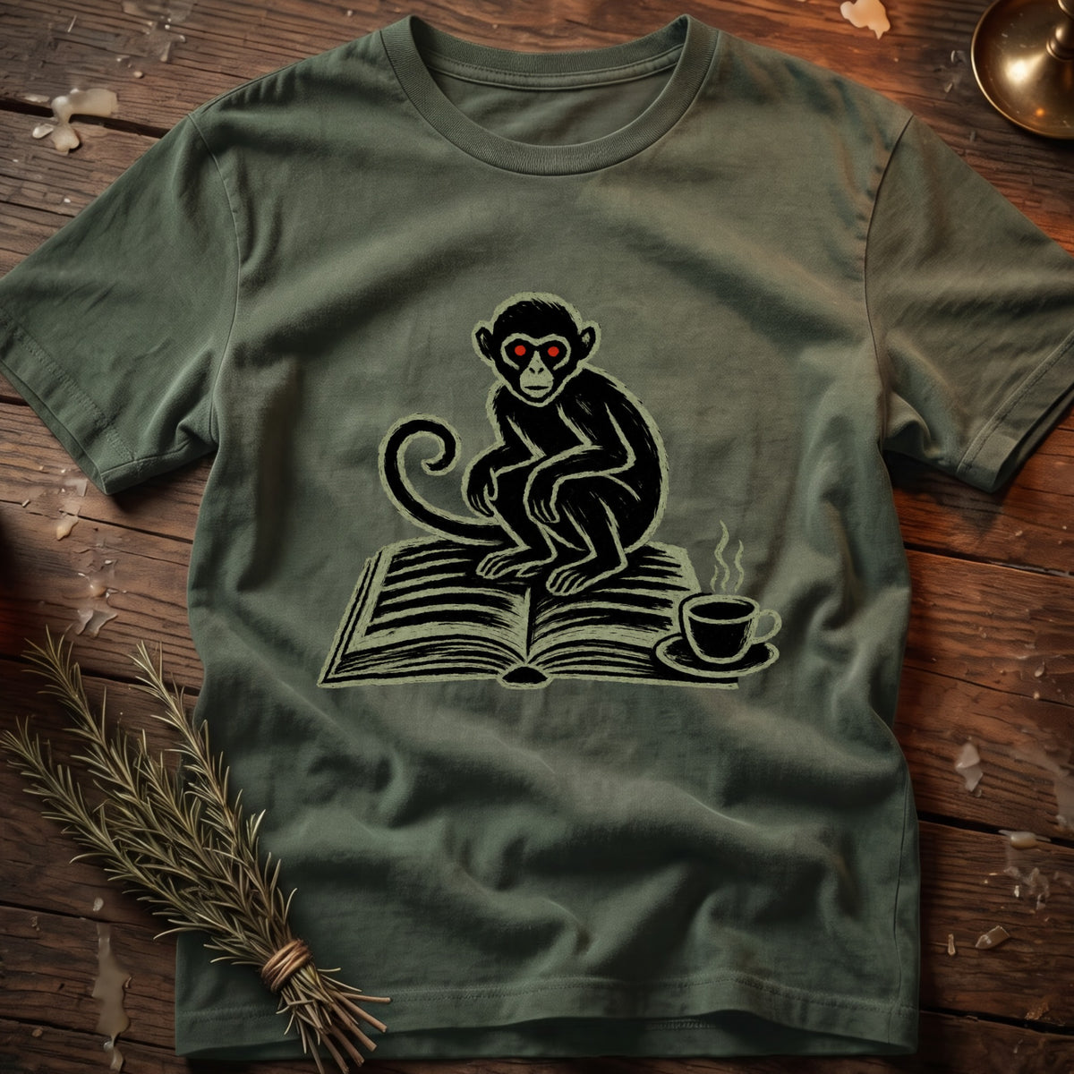 Green t-shirt with a black monkey with red eyes sitting on an open book and a coffee cup.