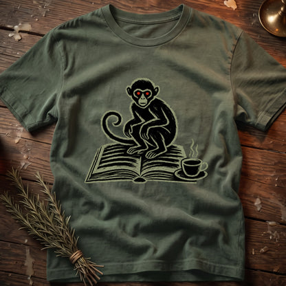 Green t-shirt with a black monkey with red eyes sitting on an open book and a coffee cup.