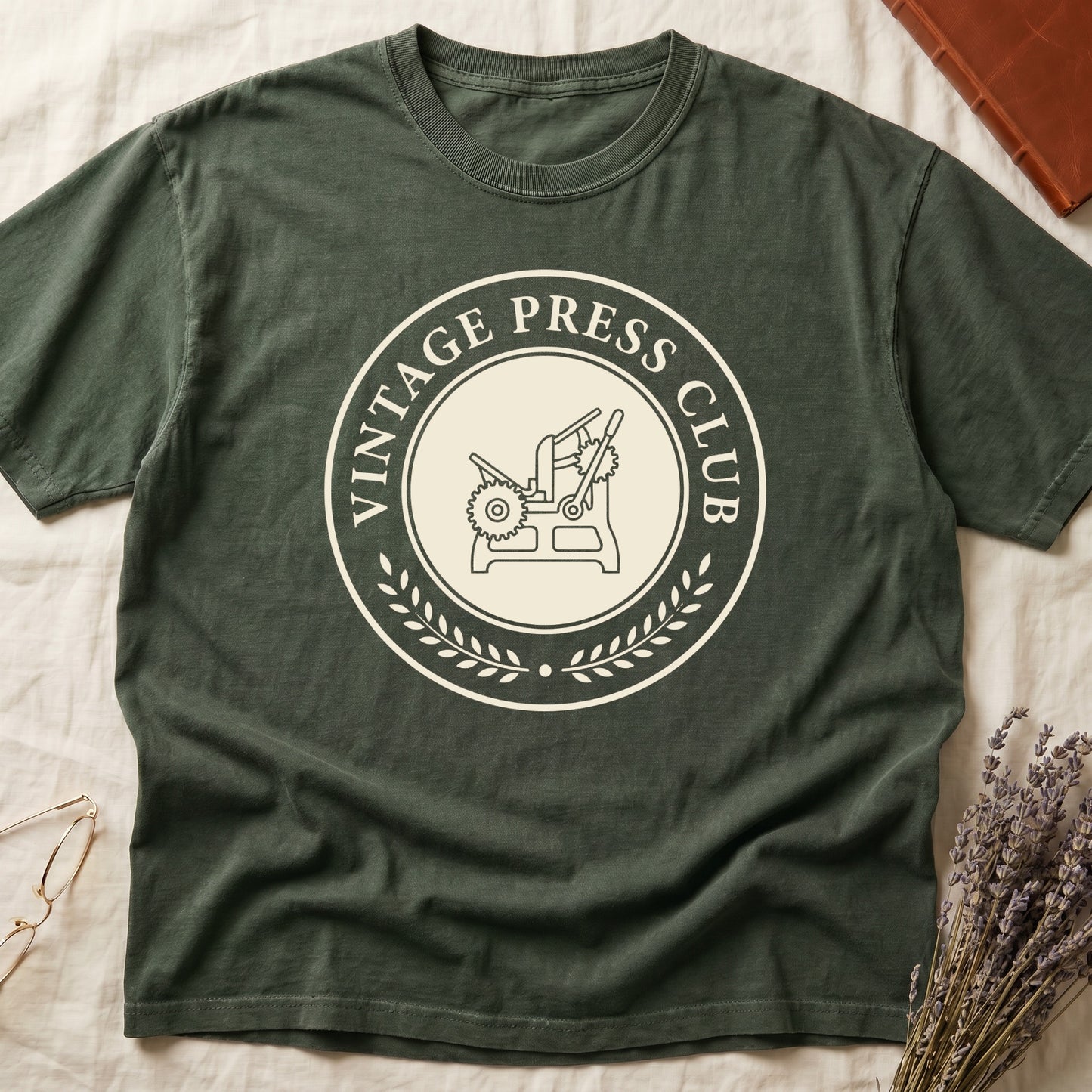 Green tee with circular letterpress badge, "VINTAGE PRESS CLUB" in serif capitals, antique printing press in cream linework.