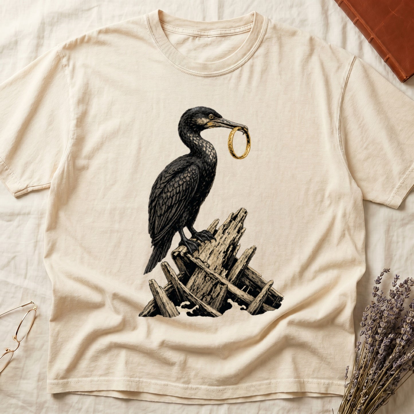 T-shirt with cormorant bird holding golden ring, standing on driftwood.