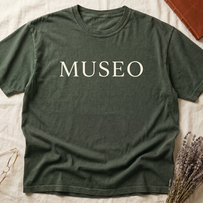Green tee with "MUSEO" in oversized cream serif capitals, minimalist typographic design.