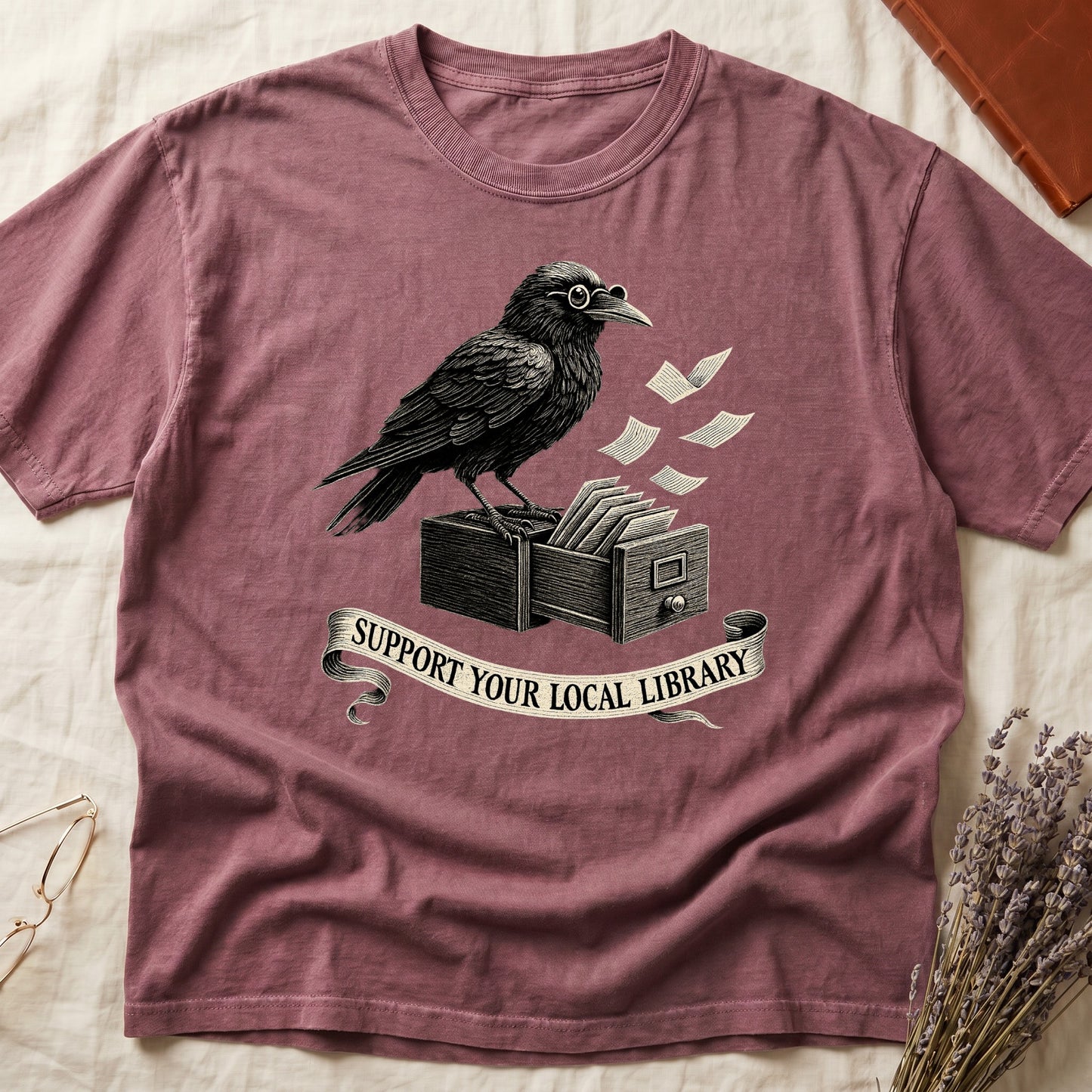 Blue Jean tee with raven writing on "823.4" parchment by candlelight, ink jar beside, "MIDNIGHT CATALOGUER" banner above.