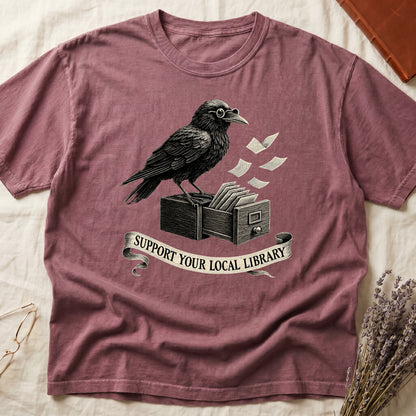 Blue Jean tee with raven writing on "823.4" parchment by candlelight, ink jar beside, "MIDNIGHT CATALOGUER" banner above.