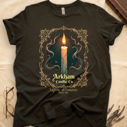 Military Green tee with lit candle, smoke, ornate gold filigree border, "Arkham Candle Co.," "Lighting the Darkness Since 1920."