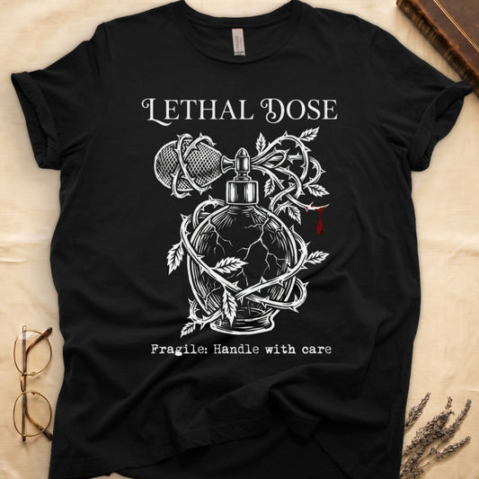 Black tee with cracked perfume bottle wrapped in thorns, blood drop, "LETHAL DOSE" top, "Fragile: Handle with care" below.