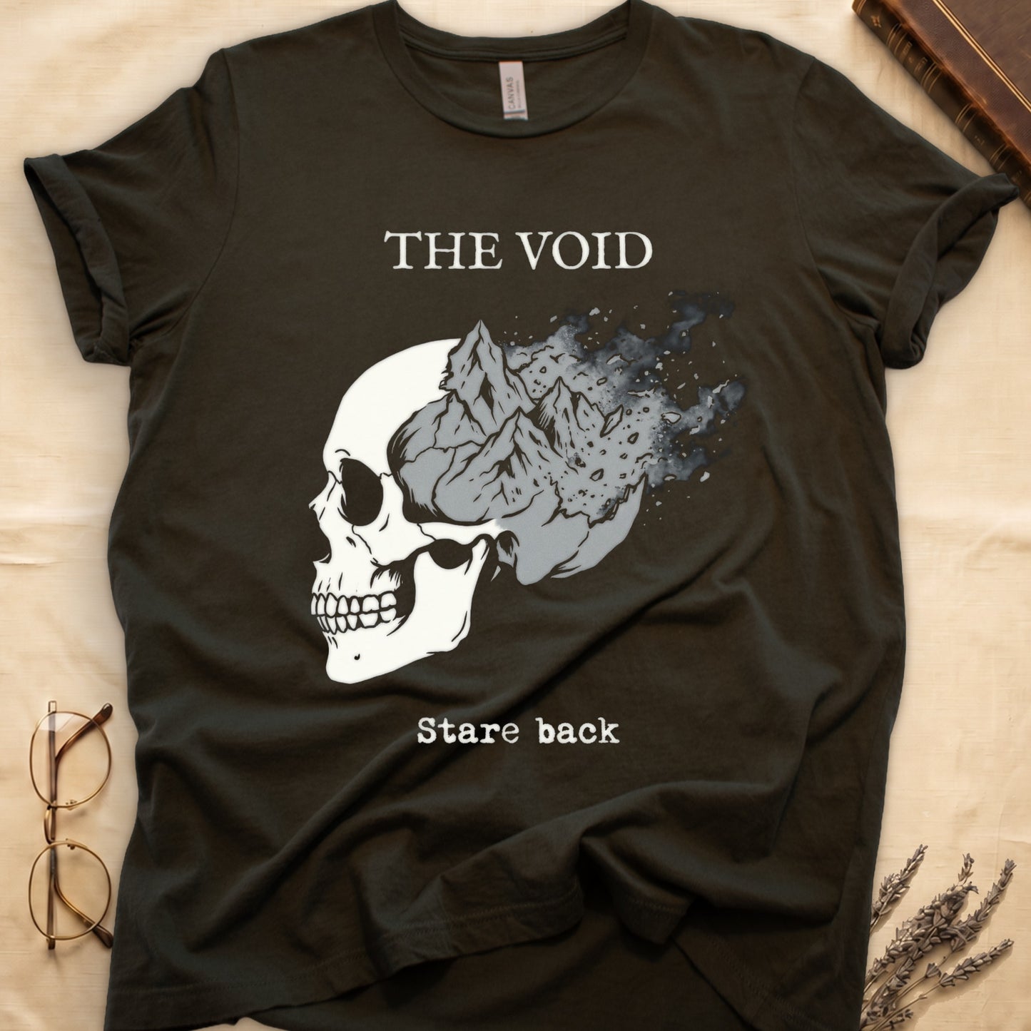 Military Green tee with skull eroding into mountain landscape and stardust, "THE VOID" top, "Stare back" typewriter below.