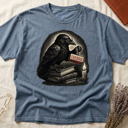 Blue Jean tee with bespectacled raven on stacked books, holding wooden "OVERDUE" stamp, lit candle beside, dawn glow behind.