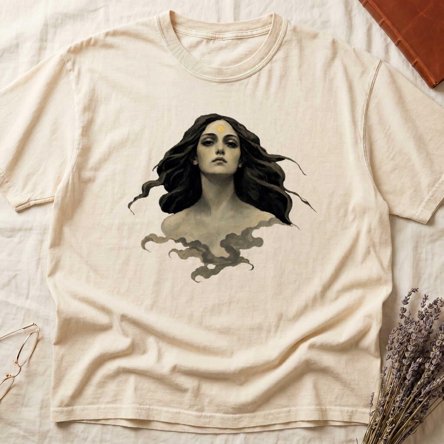 Beige t-shirt with graphic of a woman's face surrounded by dark hair and smoke.