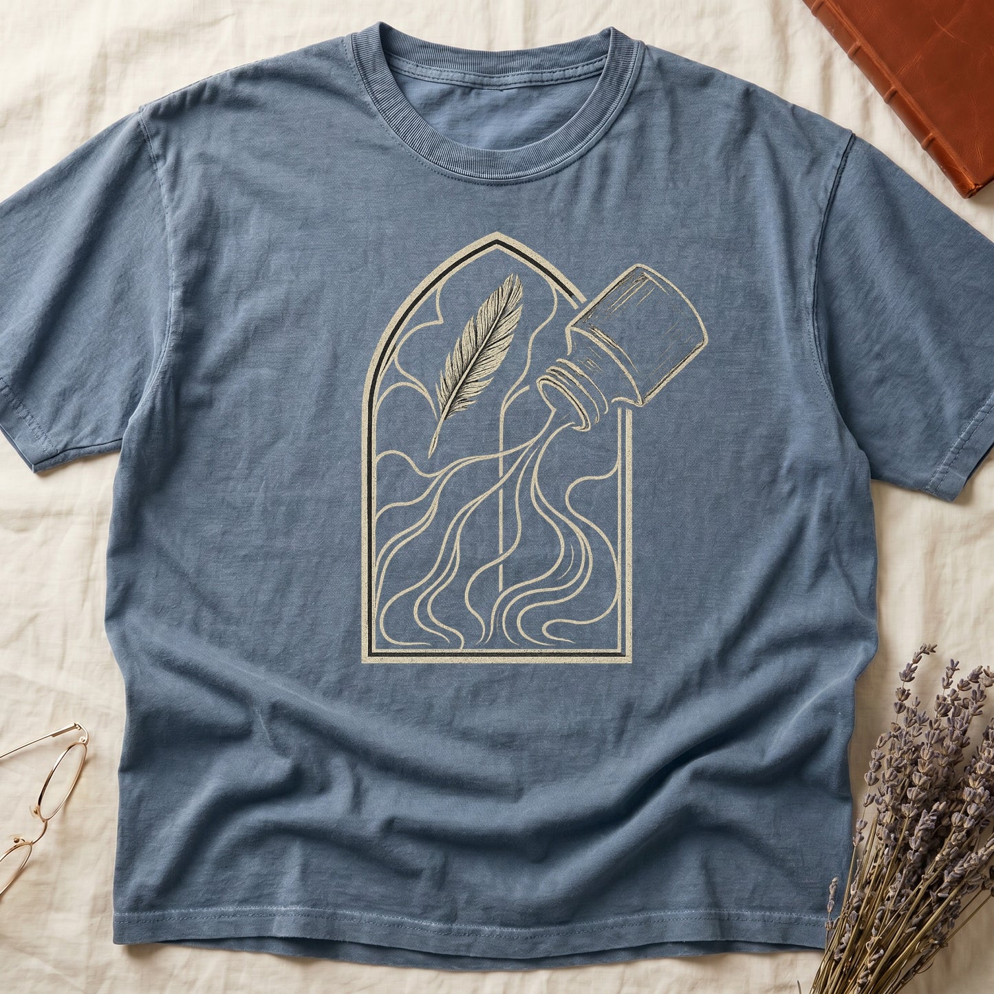 Blue Jean tee with sepia gothic arch, feather quill on left and tipped ink bottle on right spilling ink in curling tendrils.